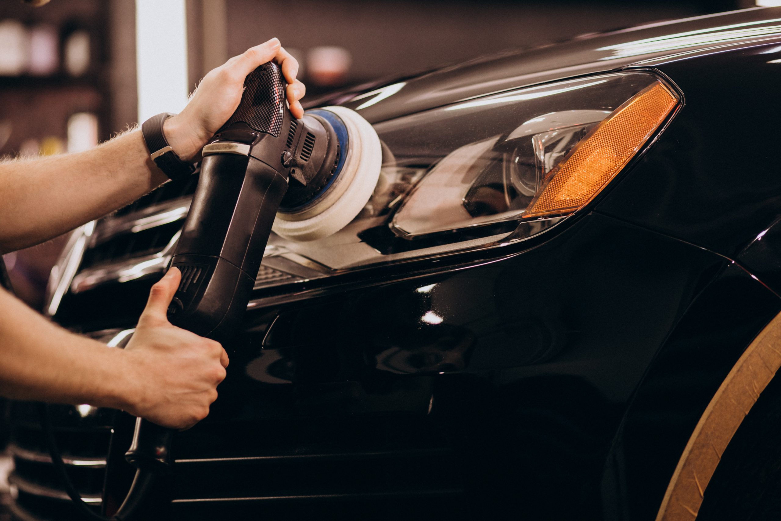 Machine polishing car paint to remove swirl marks and enhance gloss during detailing service.
