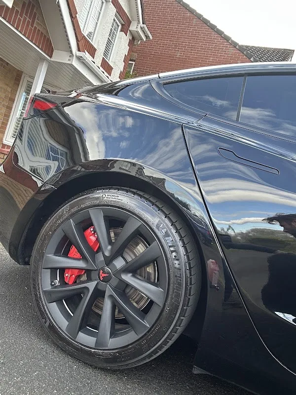Black Tesla Model 3 with red calipers after a ceramic wax finish